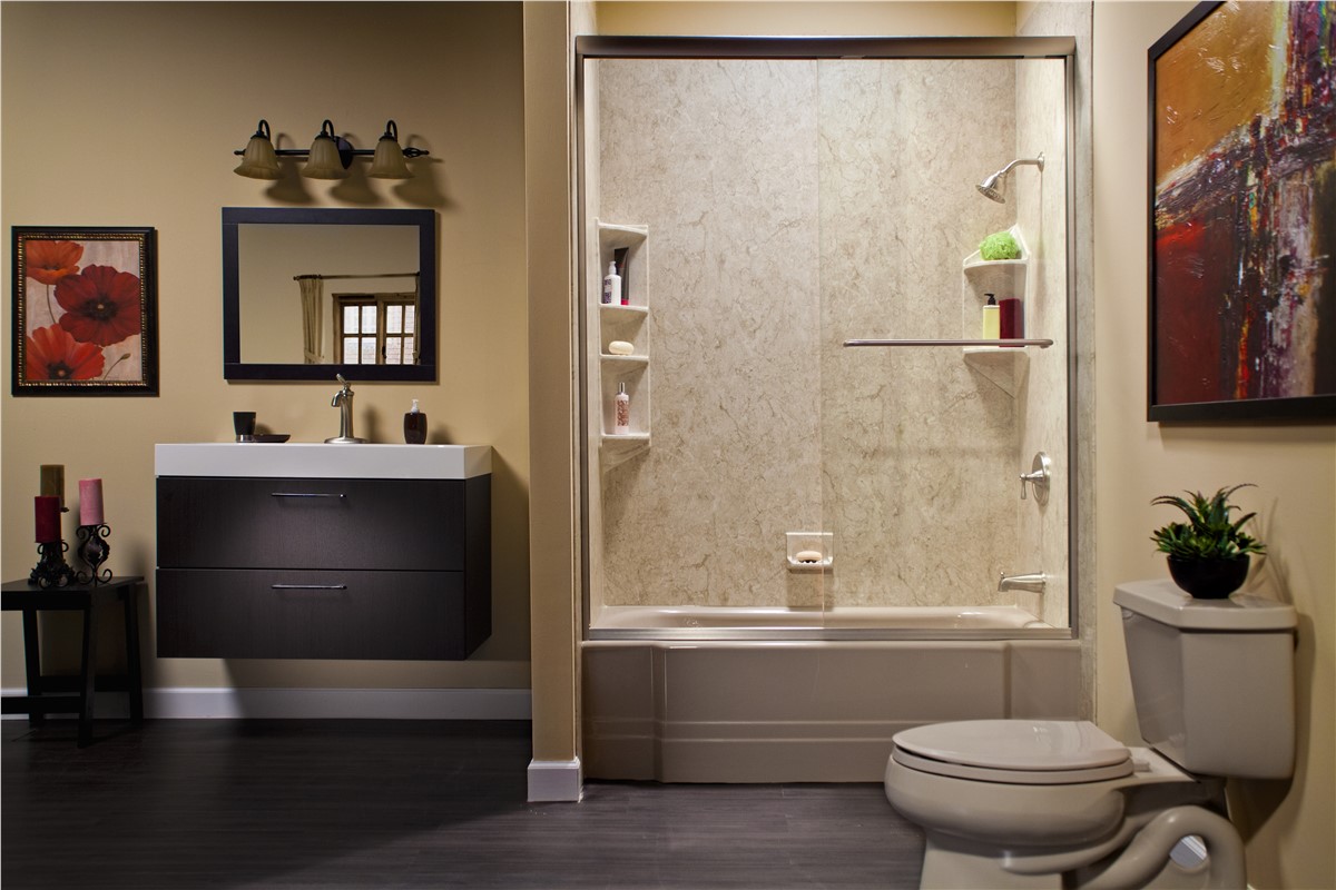 A clean bathroom featuring a toilet, sink, and shower, with neutral-colored tiles and bright lighting.