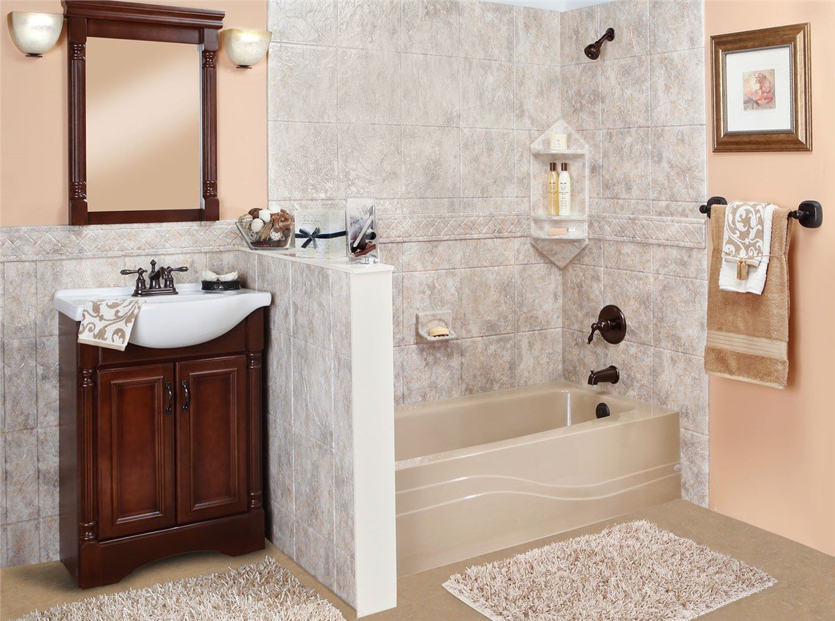 A warm bathroom with a beige tiled bathtub, bronze fixtures, and a dark wood vanity with framed mirror.
