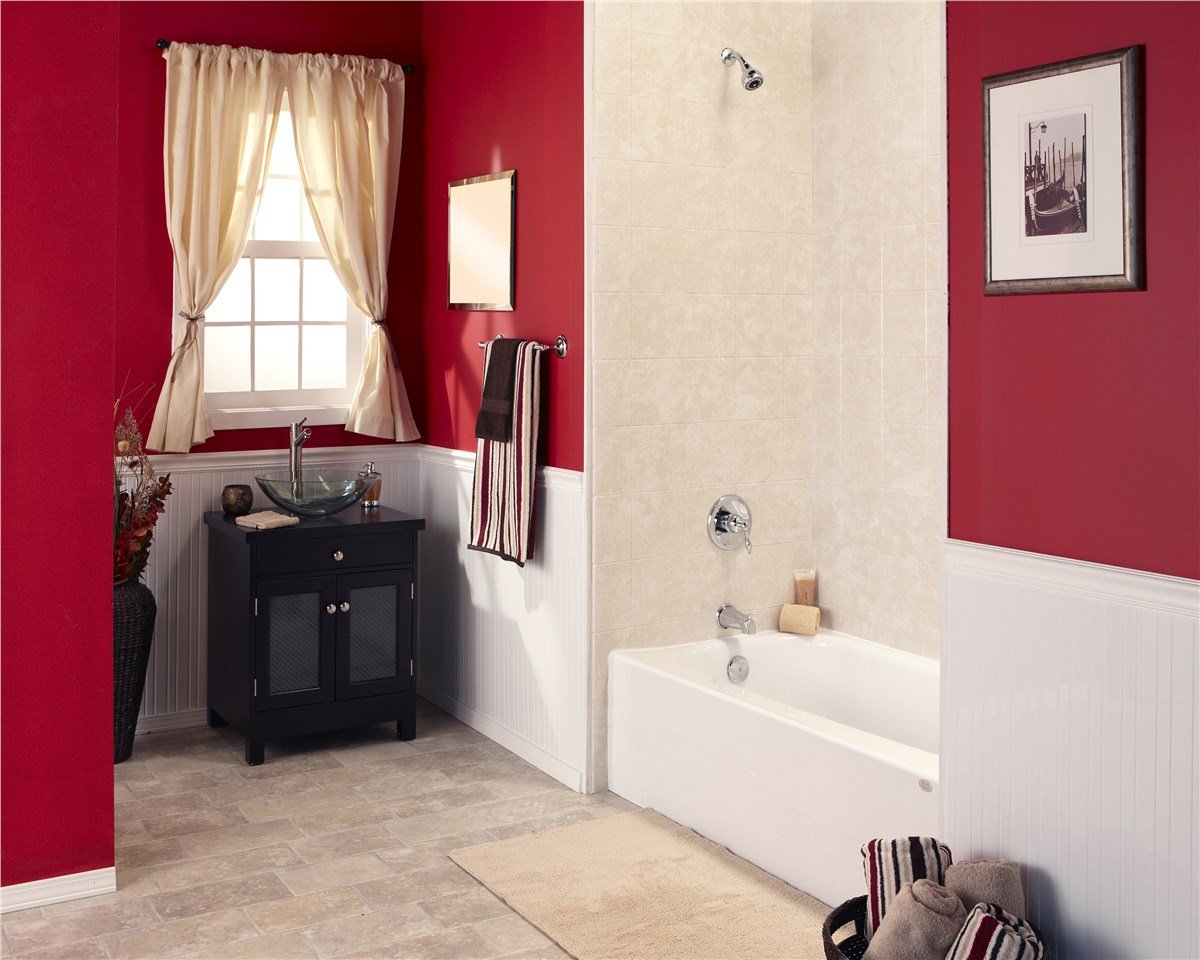 A stylish bathroom with red and white walls, a black vanity, and a tiled bathtub with chrome fixtures.