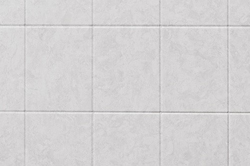 A white tiled wall featuring a modern shower head mounted above