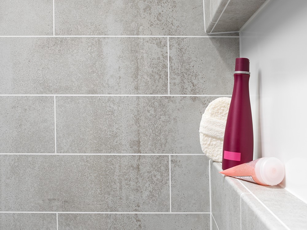 A shower scene featuring a bottle of shampoo and a hairbrush on a shelf.