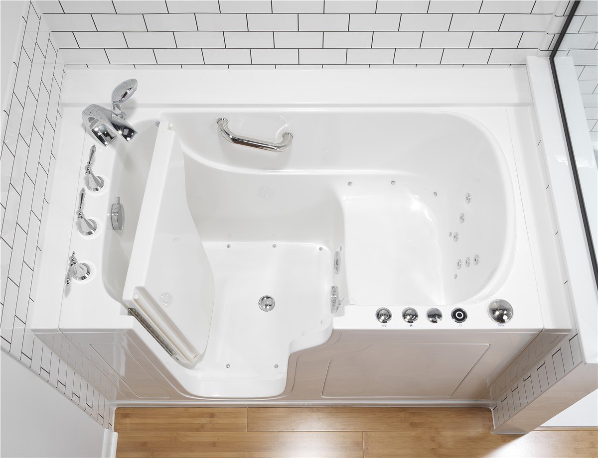 A white bathtub with a shower head above it, alongside a toilet in a bathroom setting.