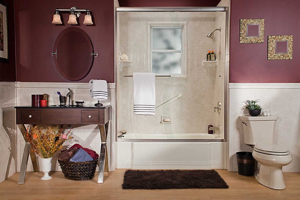A clean bathroom featuring a toilet, sink, and shower, with neutral-colored tiles and bright lighting.