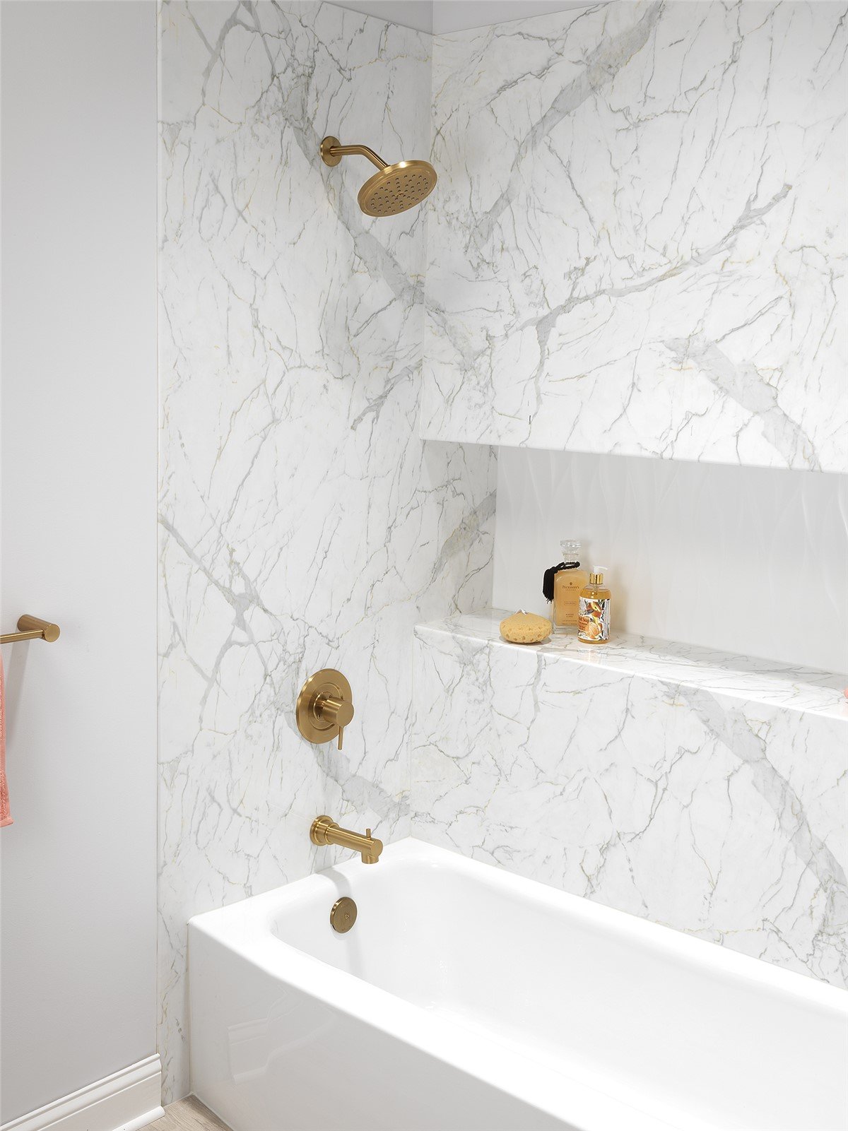 A white bathtub with gold fixtures set against elegant marble walls.