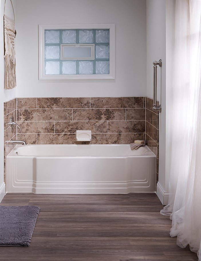 A modern bathroom featuring a bathtub and a shower, with neutral-colored tiles and natural light.